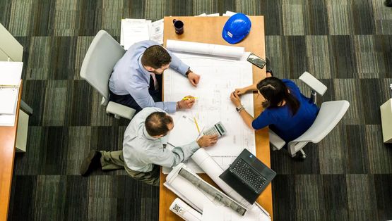 Illustrasjon - bilde av arkitekter rundt et bord med arbeidstegninger